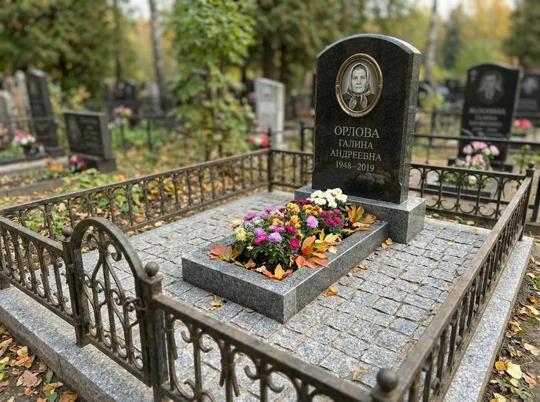 Благоустроенное захоронение с гранитной плиткой, оградой и цветником в Москве