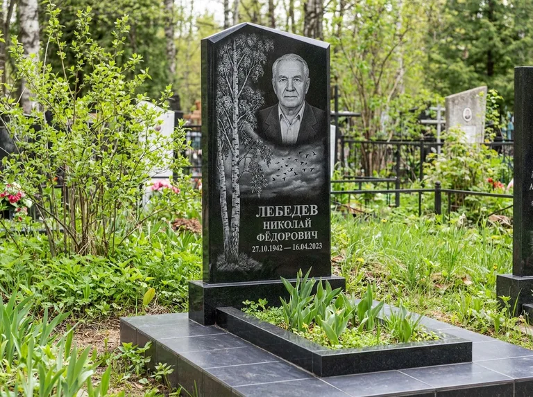 Памятник с гравировкой берёзы: вертикальная стела со скошенным верхом — берёза и стая птиц в небе, гранитный цоколь с тёмной плиткой, работа «Лебедев» в Москве