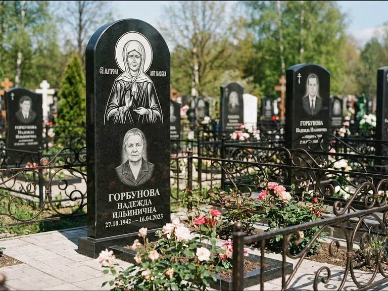 Памятник с гравировкой иконы: стела с арочным верхом и киотом под образ — гравировка образа Матроны Московской, гранитный цоколь с тёмной плиткой, работа «Ковалёв» в Москве