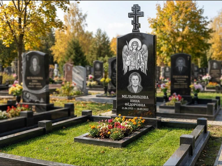 Памятник с гравировкой иконы: округлая стела-медальон с ликом — гравировка Богородицы «Семистрельная», луговые травы и полевые цветы за участком, работа «Гущин» в Москве