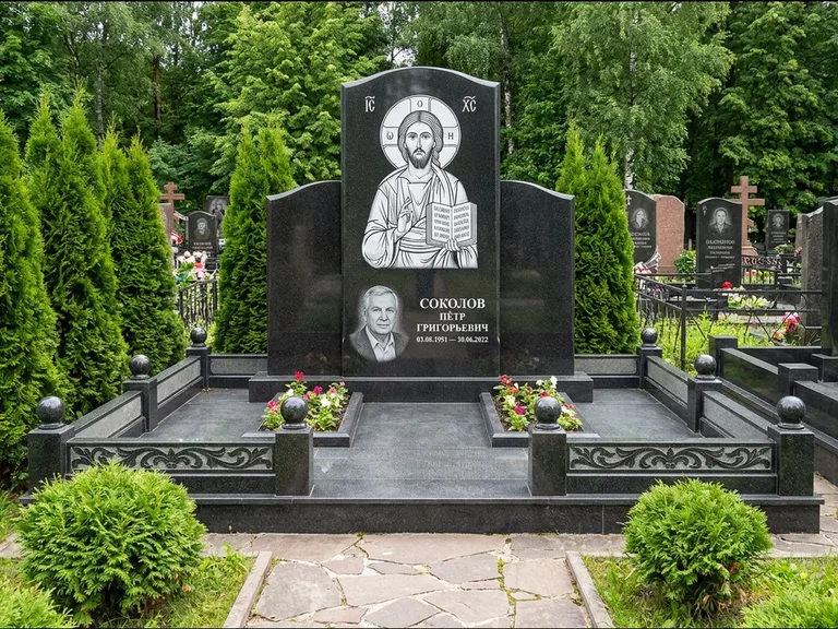 Памятник с гравировкой иконы: широкая горизонтальная лежачая плита-стела — икона в резной рамке-киоте, серая гравийная отсыпка с бордюром, работа «Богданова» в Москве