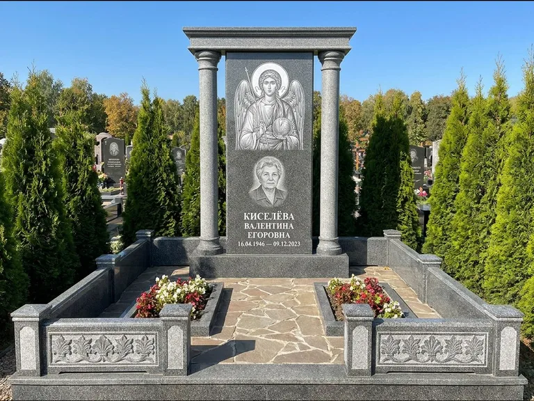 Памятник с гравировкой иконы: массивная стела с двускатным навершием-домиком — гравировка Николая Чудотворца, живая изгородь из туи, работа «Журавлёв» в Москве