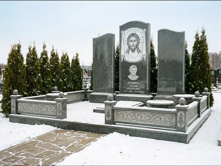 Памятник с гравировкой иконы: узкая вертикальная стела-пилон с ликом — икона в резной рамке-киоте, открытая лужайка без ограды, работа «Одинцов» в Москве
