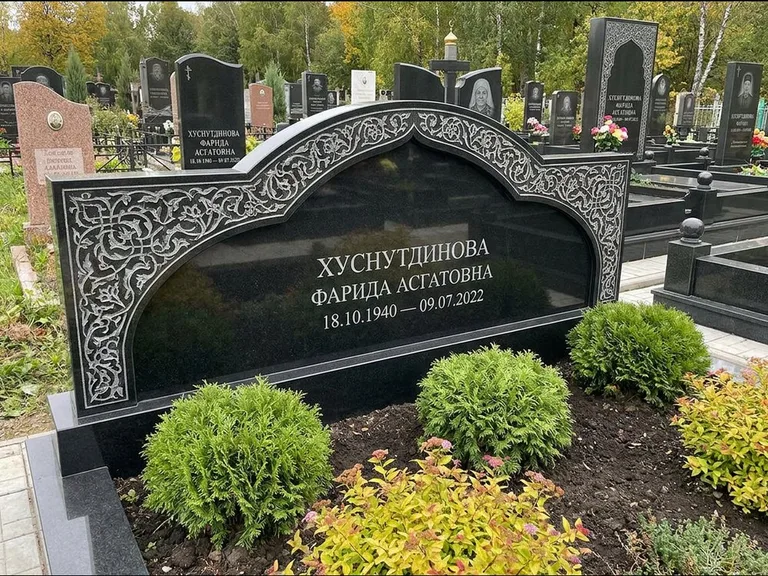 Мусульманский памятник: вытянутая горизонтальная семейная стела с аркой — белая гравировка силуэта мечети с минаретами, участок с декоративными кустами, работа «Зарипова» в Москве