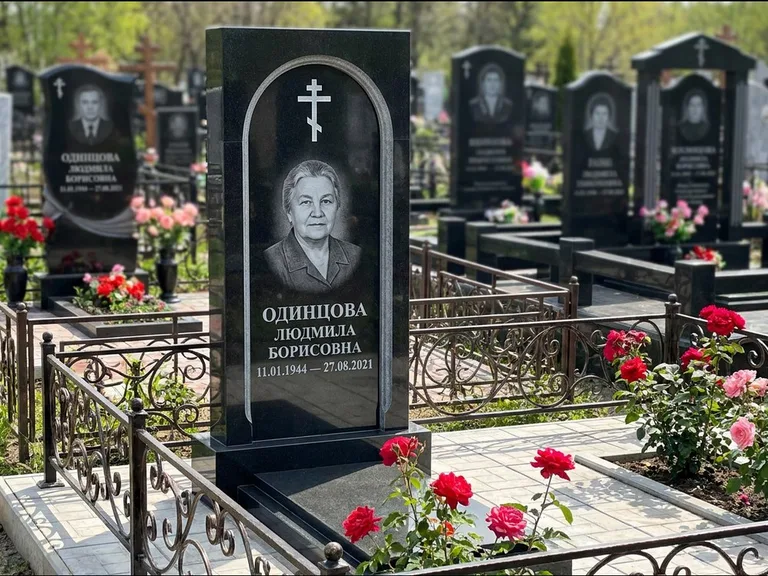Памятник из чёрного гранита — скромная невысокая стела с крестом с терновым венцом, работа «Лаврентьева» в Москве
