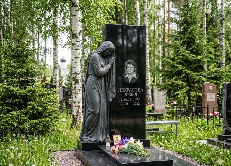 Гранитная фигура скорбящего мужчины у чёрной стелы в Москве